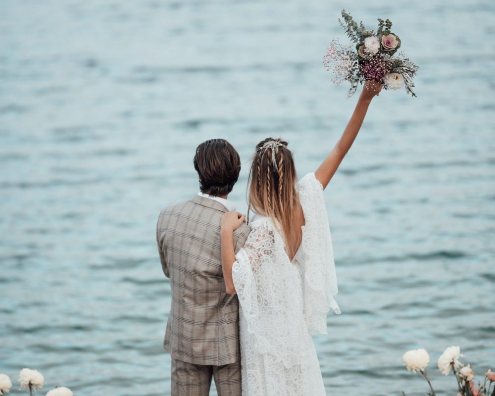 Millennial young lovely couple hugging smiling casual trust kissing at canyon loch.Lovers laughing hugs kiss at shore lake.Real people guy girl cheerful walk two in bohemian wear hand holding lifestyle fun love time.Stylish casual outfit boyfriend and girlfriend newlyweds family portrait passion tenderness.Groom in country style earth tone suit and bride in gorgeous white lace wedding dress celebrating saint valentine day.love story friends in spending together romance dating background nature